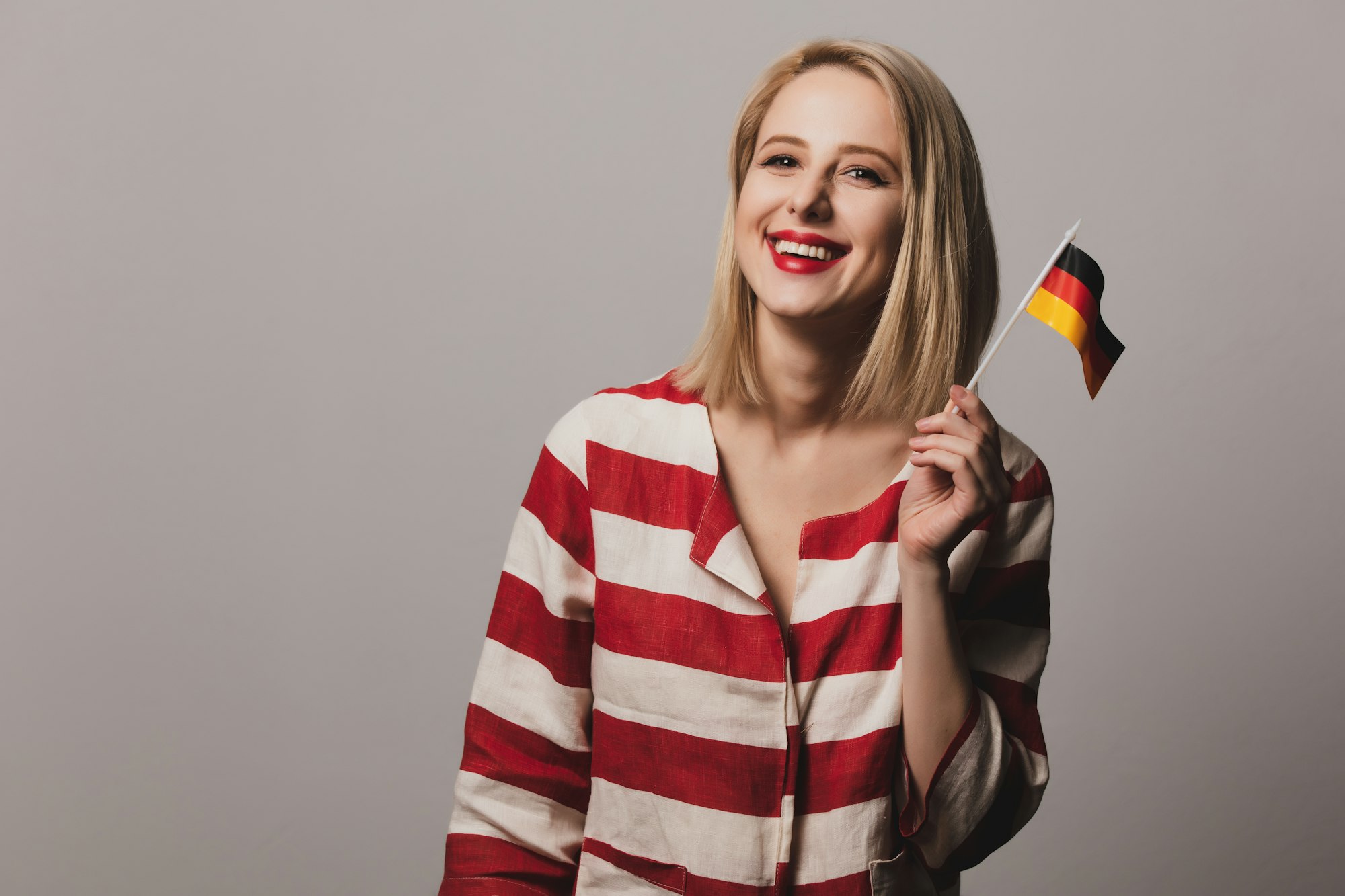 beatiful girl holds German flag on gray background